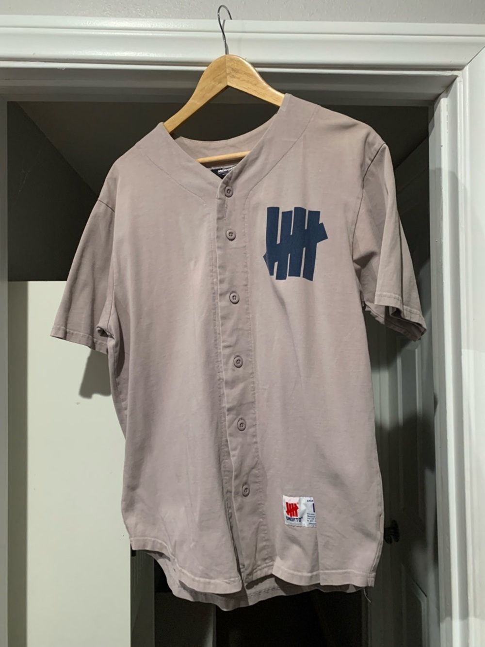 Undefeated Beige Short-Sleeve Button Baseball Jersey with Navy Logo